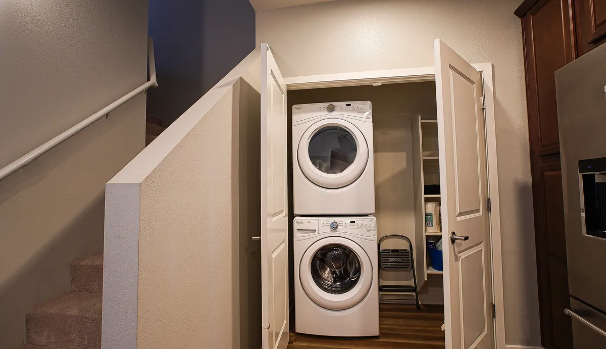 A practical laundry space with washer and dryer, neatly organized and adjacent to a staircase. The area is clean and functional, underscoring the benefits of extended living with full amenities for self-sufficiency.