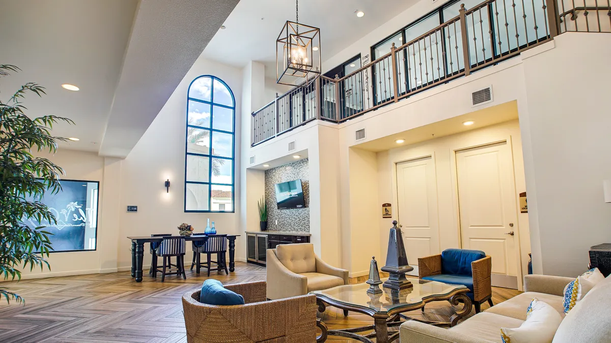 A bright and spacious open-plan area with a large arched window, stylish seating, a dining table, and a decorative wall with a TV. Sunlight pours in, and the setup encourages socializing and relaxation.