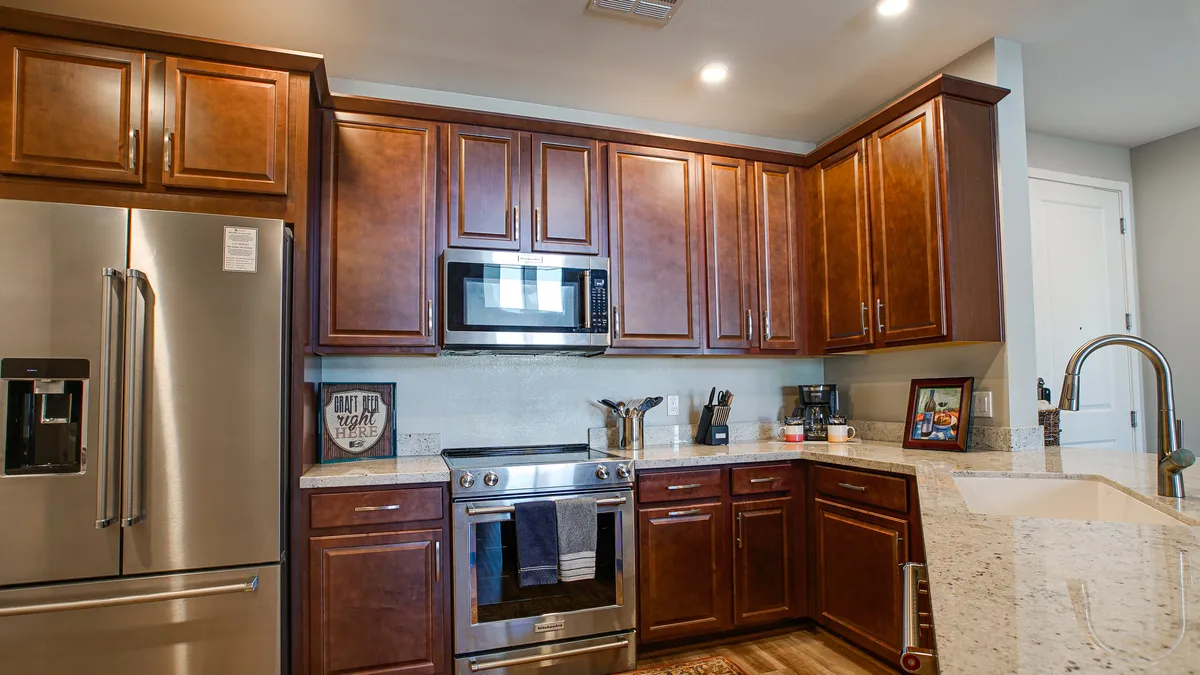 A modern kitchen with stainless steel refrigerator, granite countertops, and wooden cabinets, fully equipped for cooking and entertaining. Appliances and ample counter space highlight the practicality for daily life and culinary exploration.